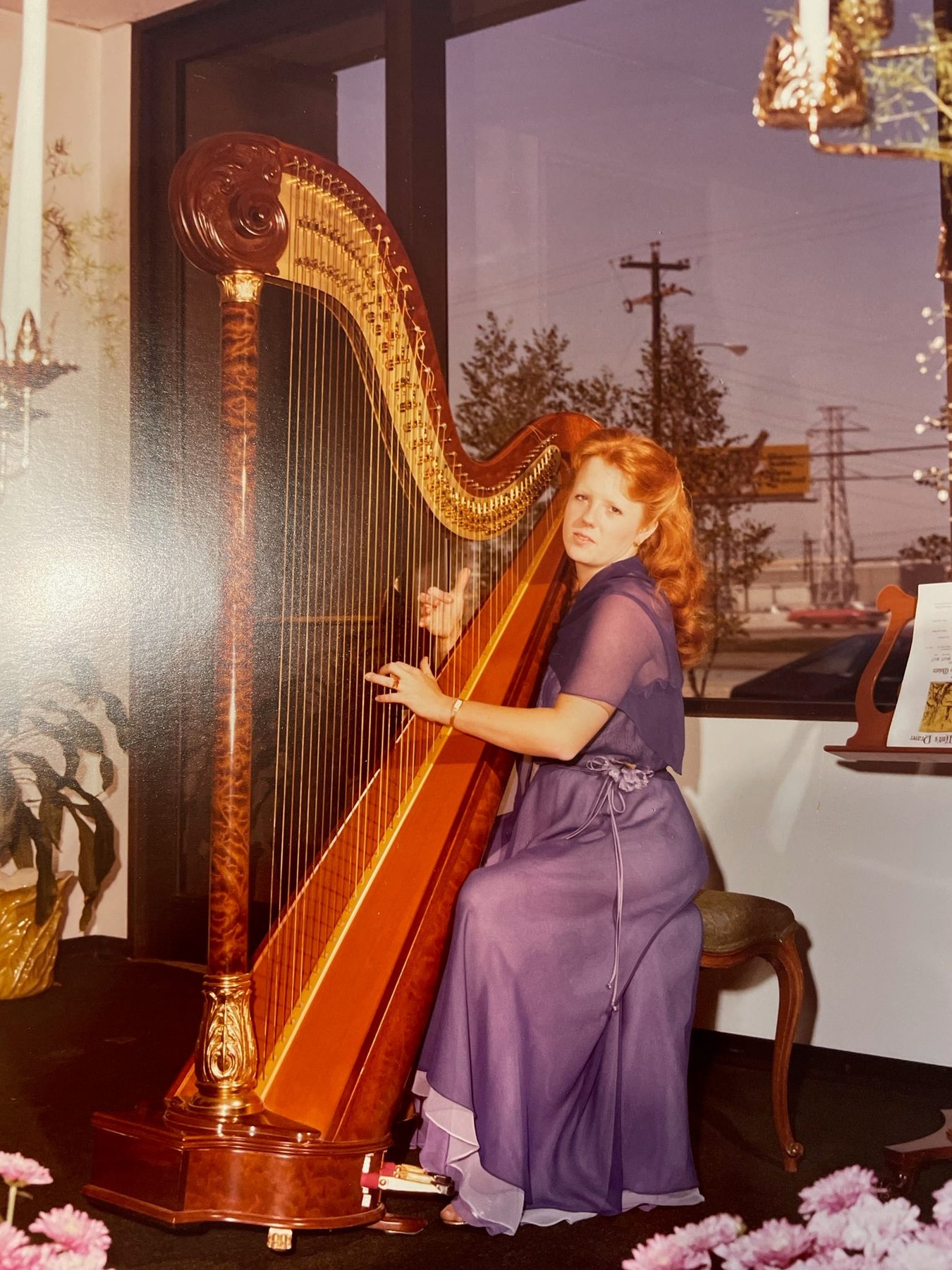 Young Guinndolyn in a lavender gown playing harp